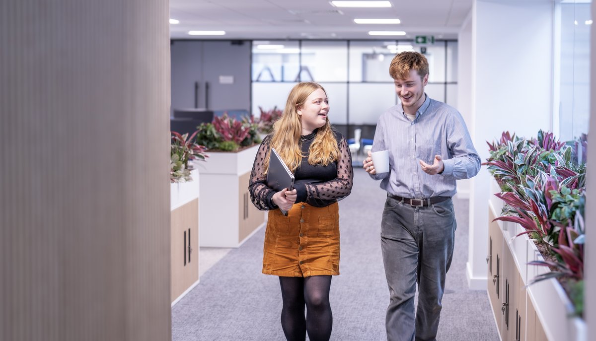 Two KBR colleagues walking and talking in the office