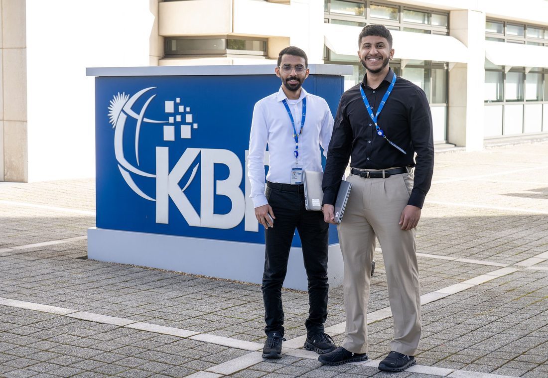 Two KBR colleagues in front of the KBR sign in Oman