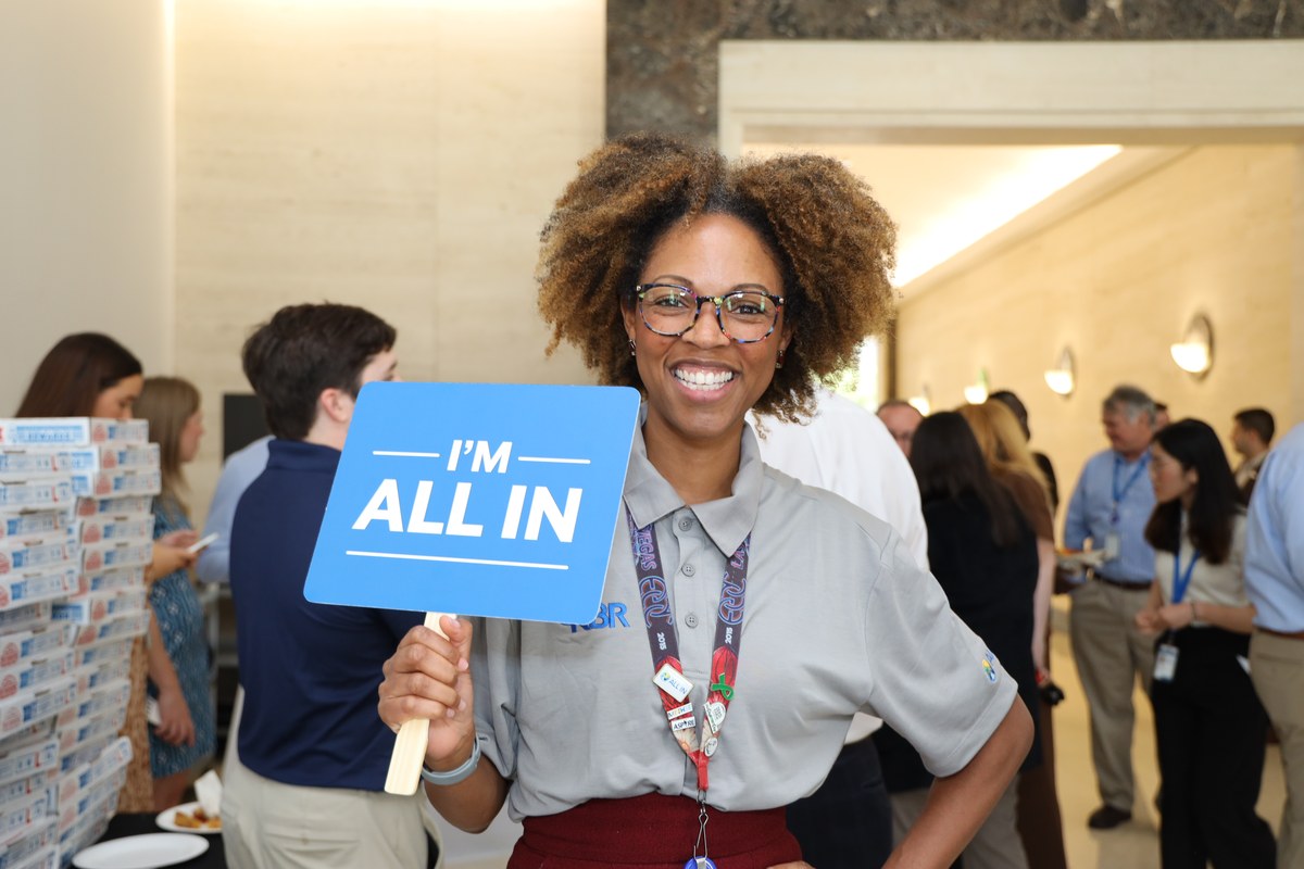KBR colleague holding an 'I'm All In' sign at a company event